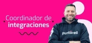 Un hombre sonríe con una sudadera negra con capucha que lleva la inscripción "puntored". A su lado se lee "Coordinador de integraciones" sobre un fondo rosa brillante.